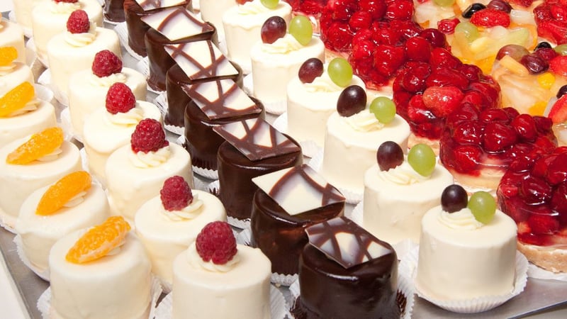 Cremetörtchen mit Toppings aus Mandarinen, Himbeeren, Weintrauben, weiteren Früchten und Schokolade; appetitlich aufgereiht